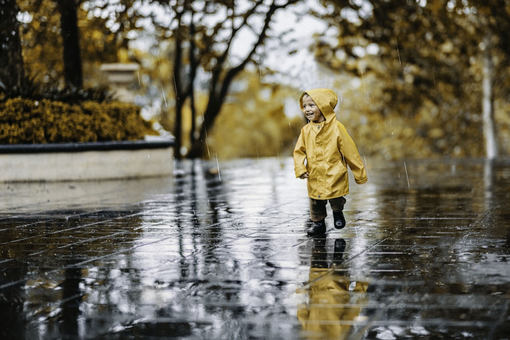 child in brown coat standing on water during daytime