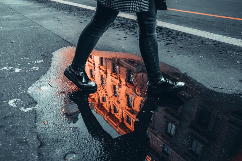 person in black leather boots standing on brown and black concrete floor