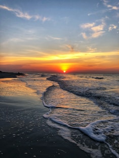 ocean waves crashing on shore during sunset