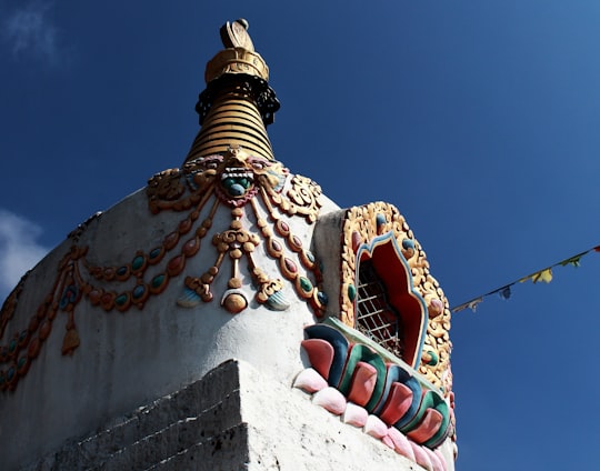 low angle photography of white and gold concrete building under blue sky during daytime in Tengboche Nepal