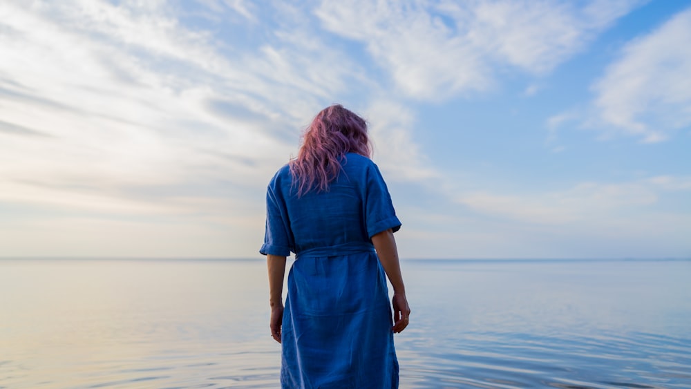 woman in blue dress standing on beach during daytime