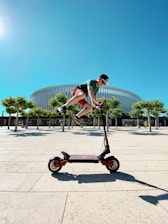 man in green t-shirt and black shorts riding black and red trike during daytime