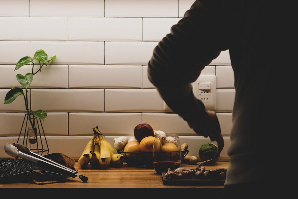 person in black jacket and green pants holding knife slicing apple fruit