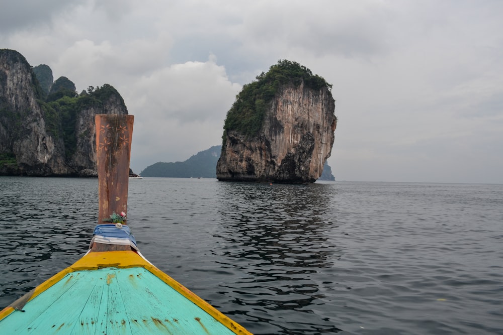 blue and brown boat on sea near brown rock formation during daytime