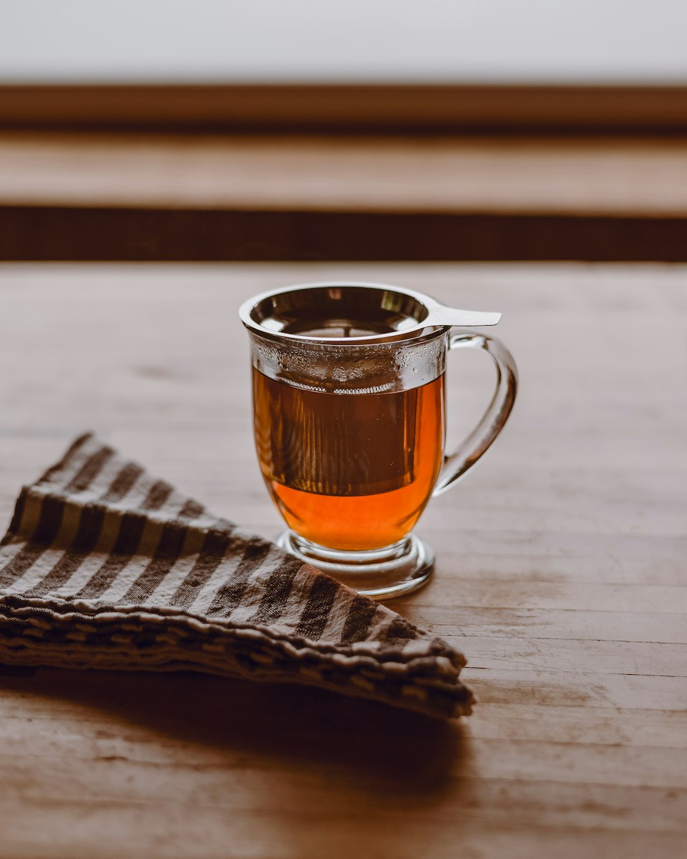 Tazza in vetro trasparente con liquido marrone su tavolo in legno marrone