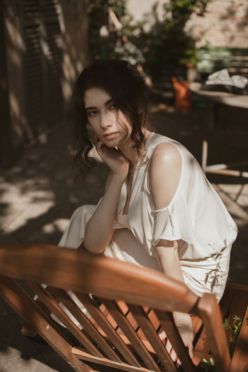 갈색 나무 벤치에 앉아 흰색 민소매 드레스를 입은 여자