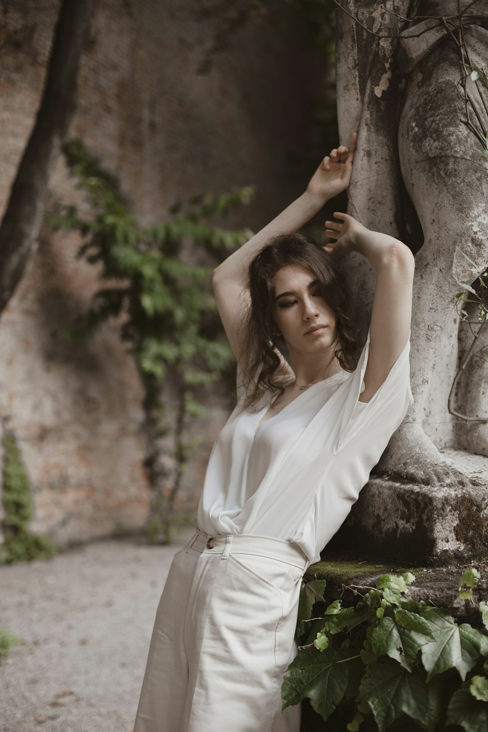 woman in white dress leaning on brown tree