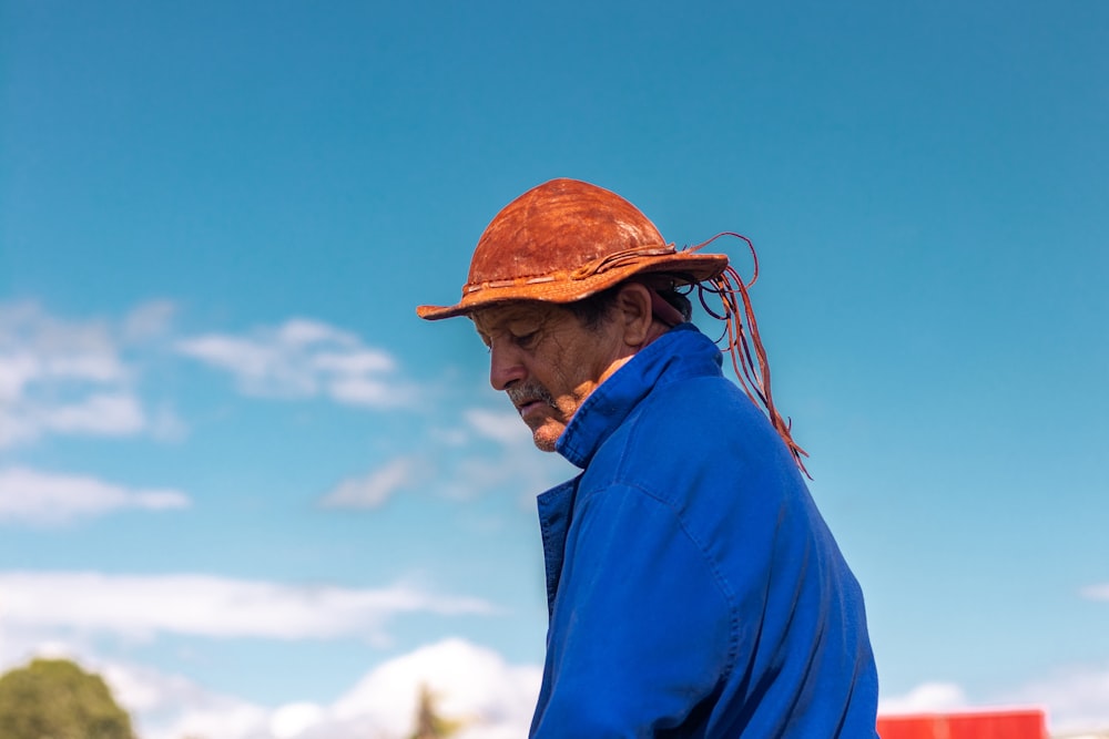 man in blue dress shirt and brown hat