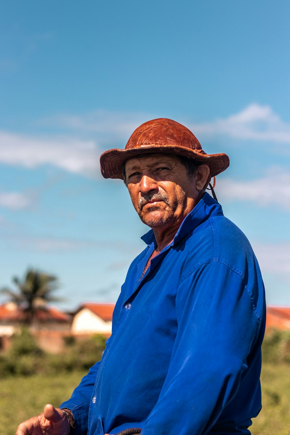 man in blue dress shirt wearing brown fedora hat