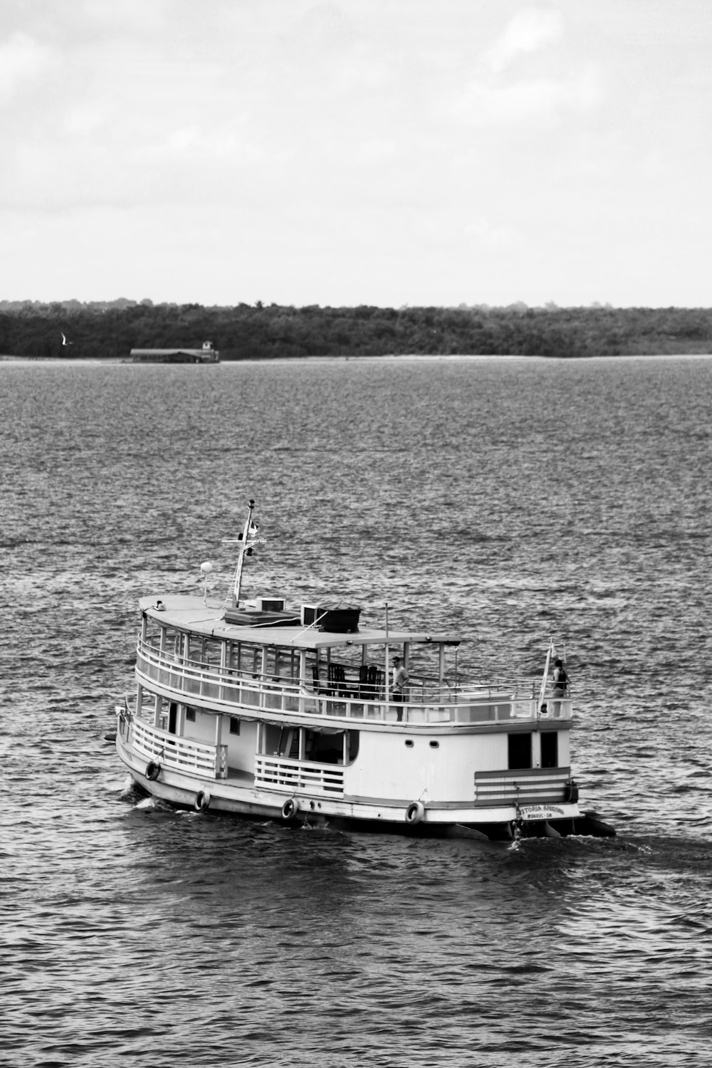 Foto en escala de grises de un barco blanco en el mar