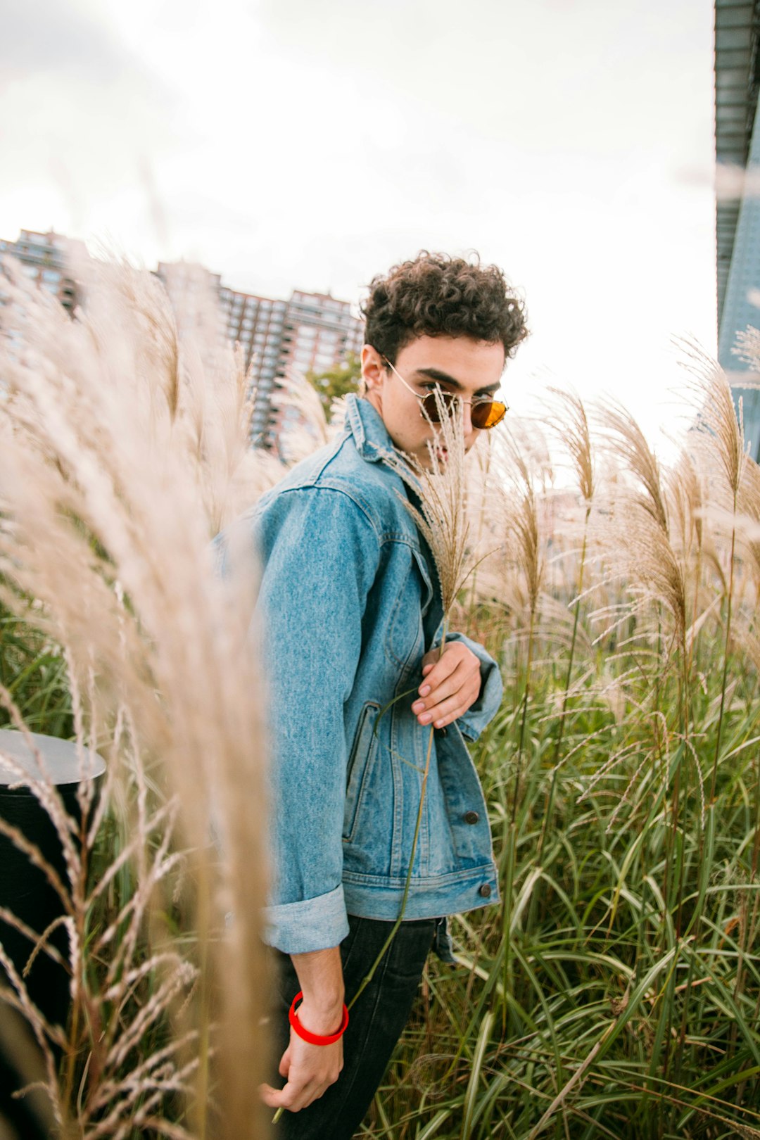 man in blue denim jacket standing on grass field during daytime