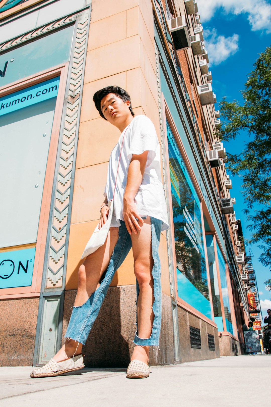 woman in white t-shirt and blue denim daisy dukes standing on brown concrete building during