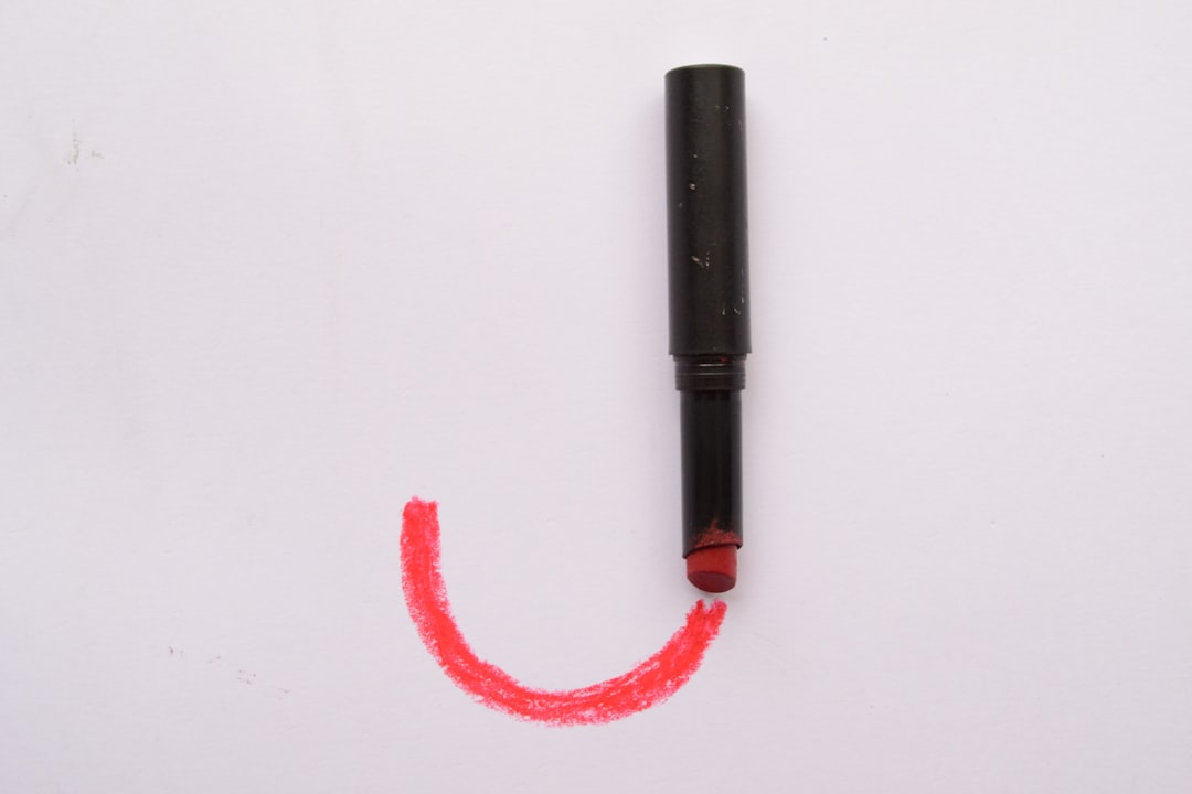black and red tube on white surface, J letter made with makeup lipstick beauty style