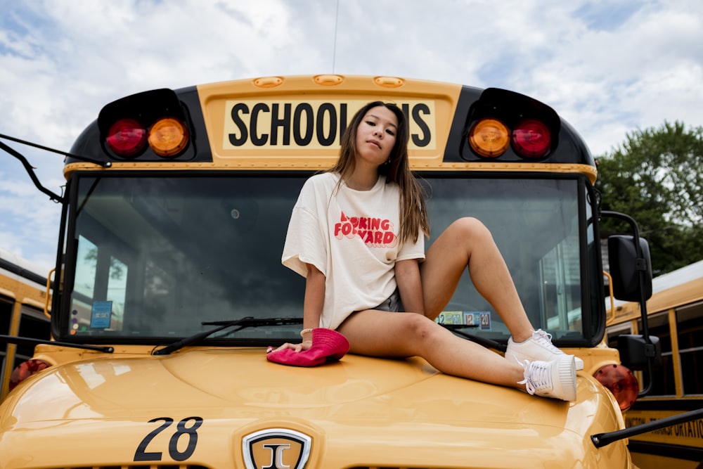 woman in white t-shirt sitting on yellow car