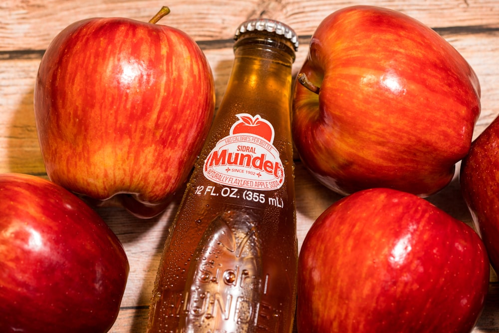 red apples beside brown and white labeled bottle