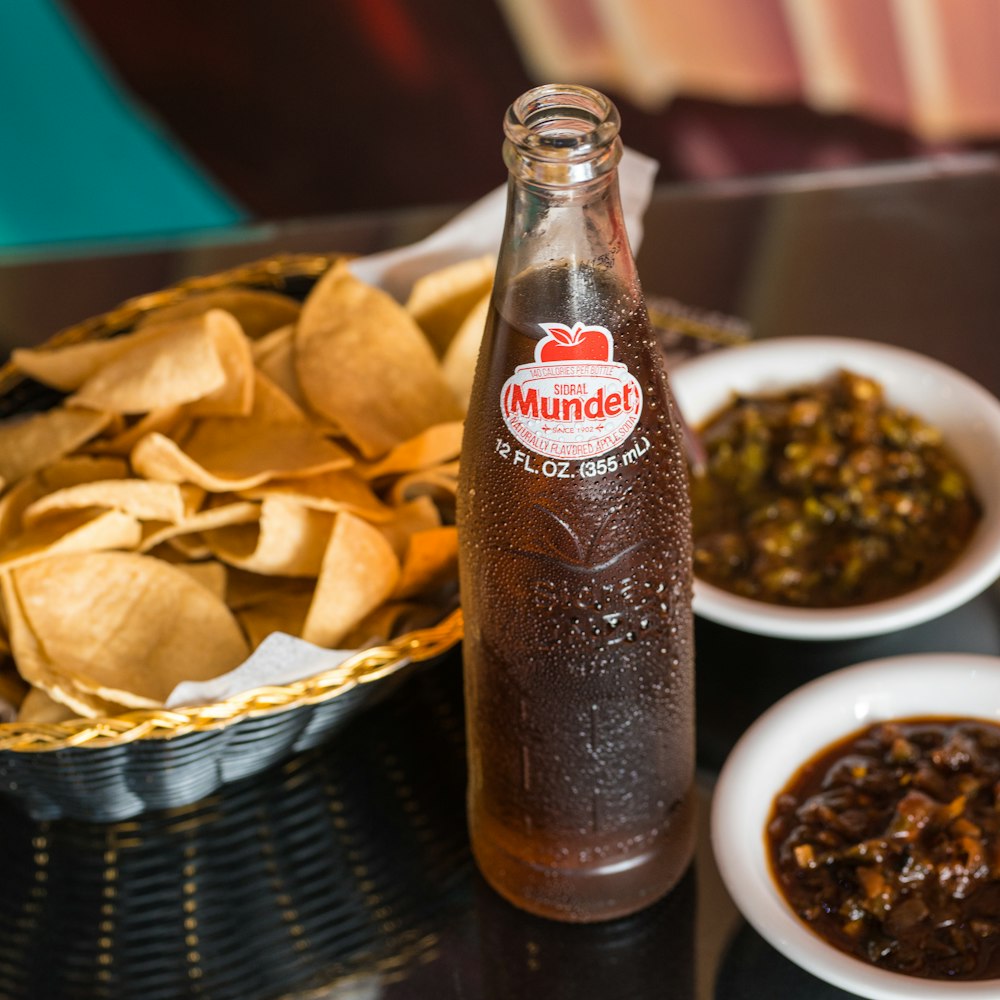 Botella de Coca Cola junto a cuenco de cerámica blanca con comida