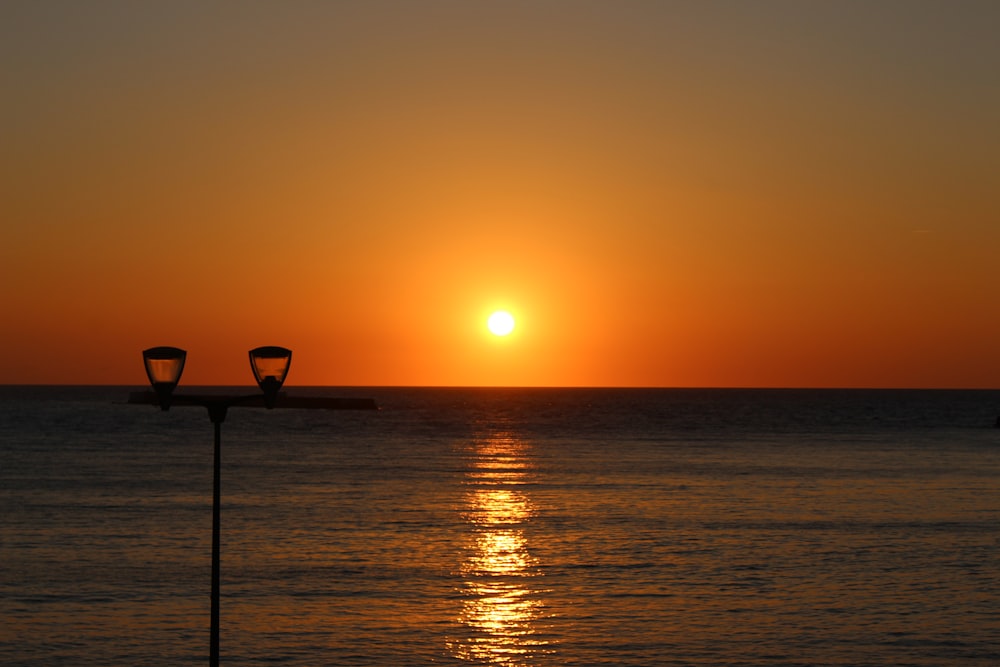Silueta de una persona de pie en una playa durante la puesta del sol