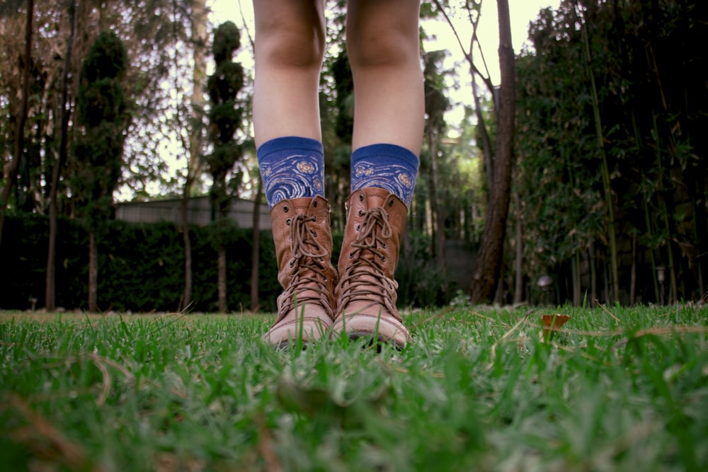 person in brown leather boots standing on green grass field during daytime