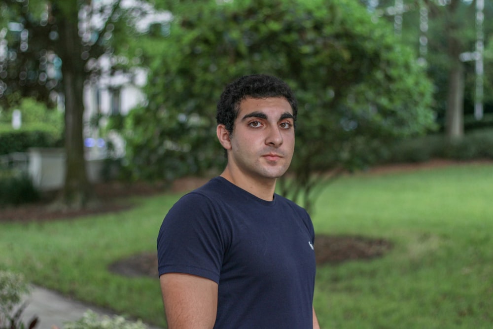 man in black crew neck t-shirt standing on green grass field during daytime