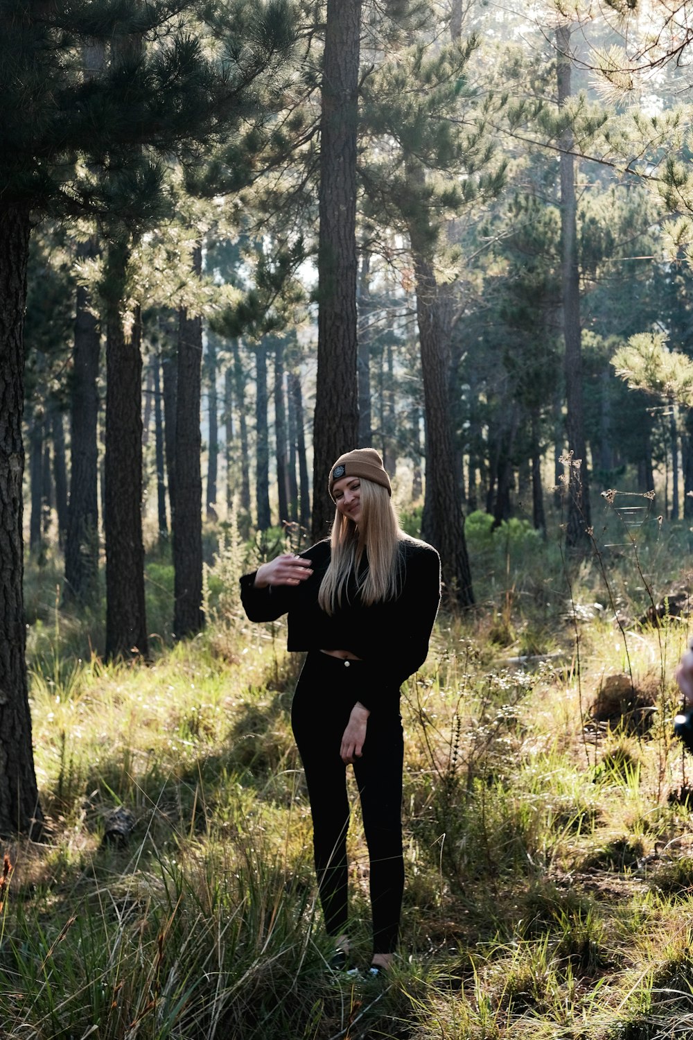 Frau in schwarzem Langarmhemd tagsüber auf Wald stehend
