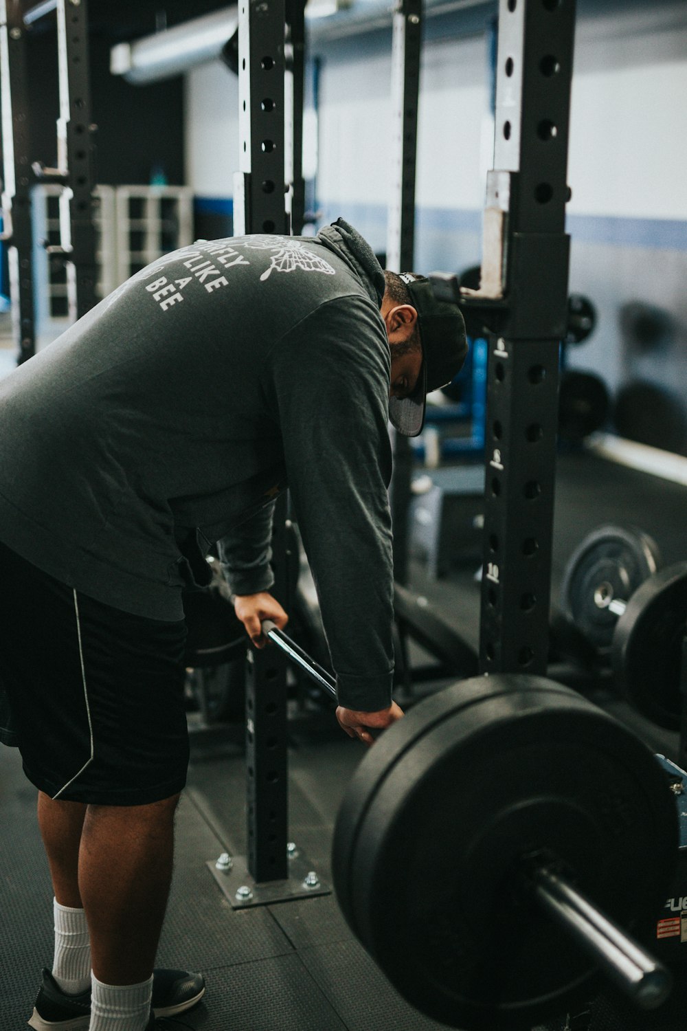 man in black t-shirt and black shorts carrying black barbell