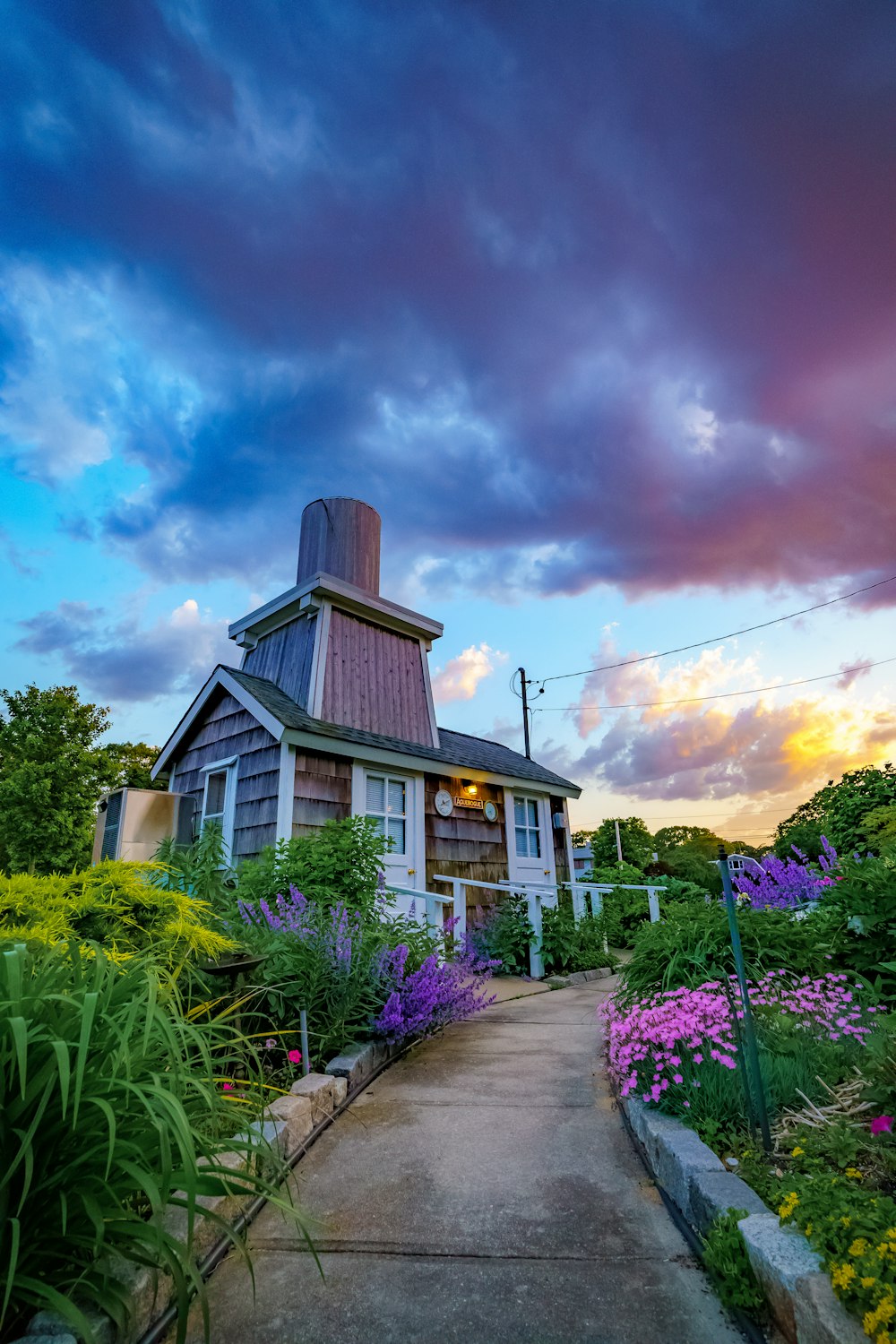 brown wooden house surrounded by green plants under blue sky during daytime