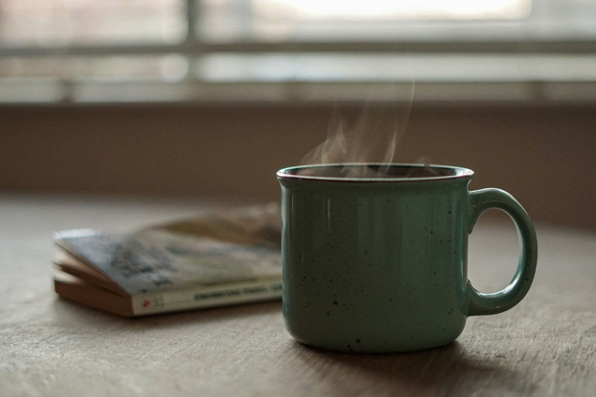 A steaming mug of coffee on a table in morning light