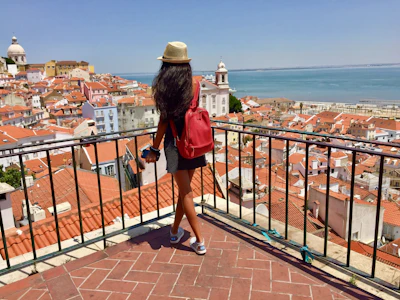 woman in red dress and brown hat standing on brown wooden dock during daytime