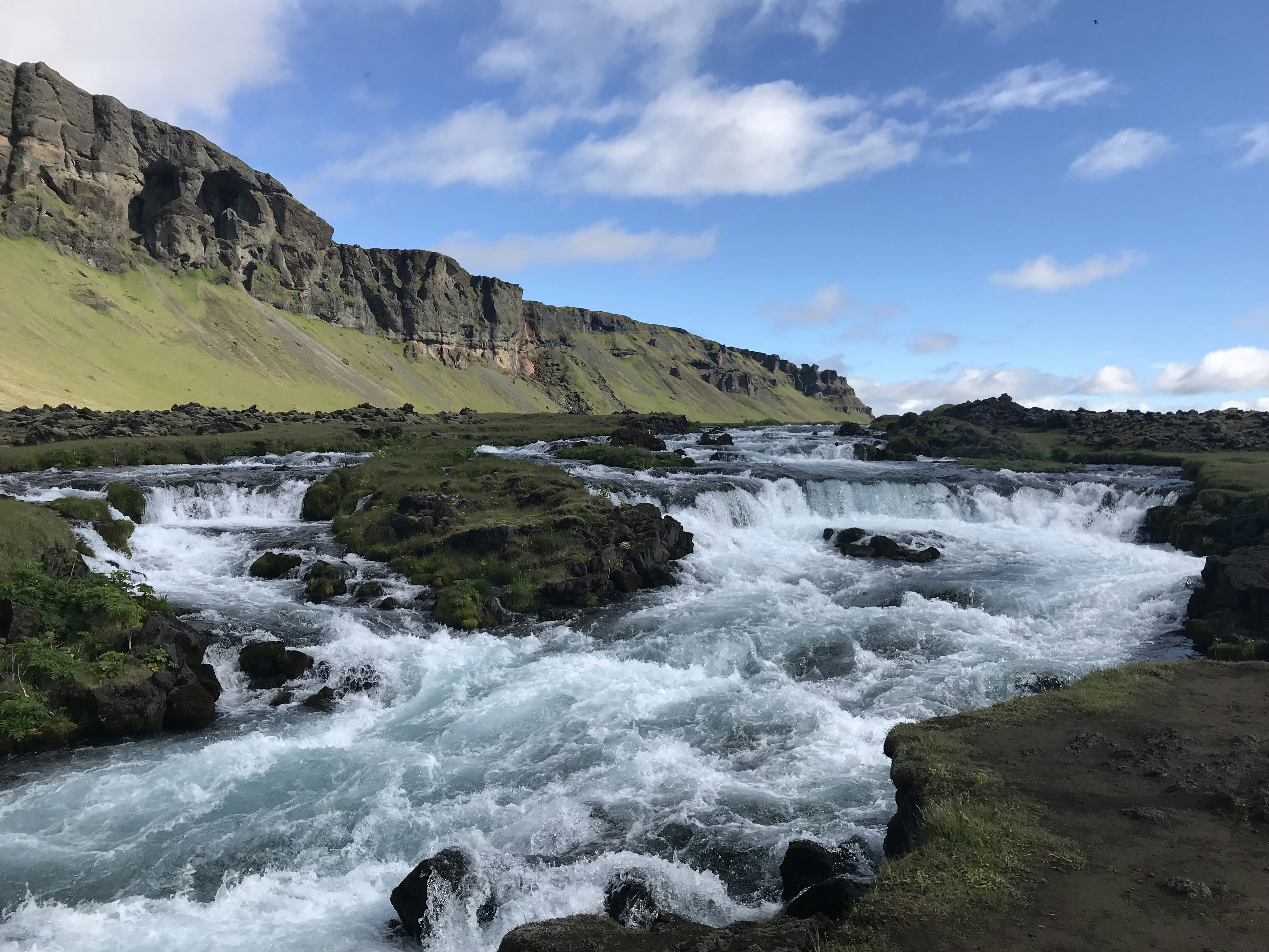 green and brown mountain beside body of water under blue sky during daytime