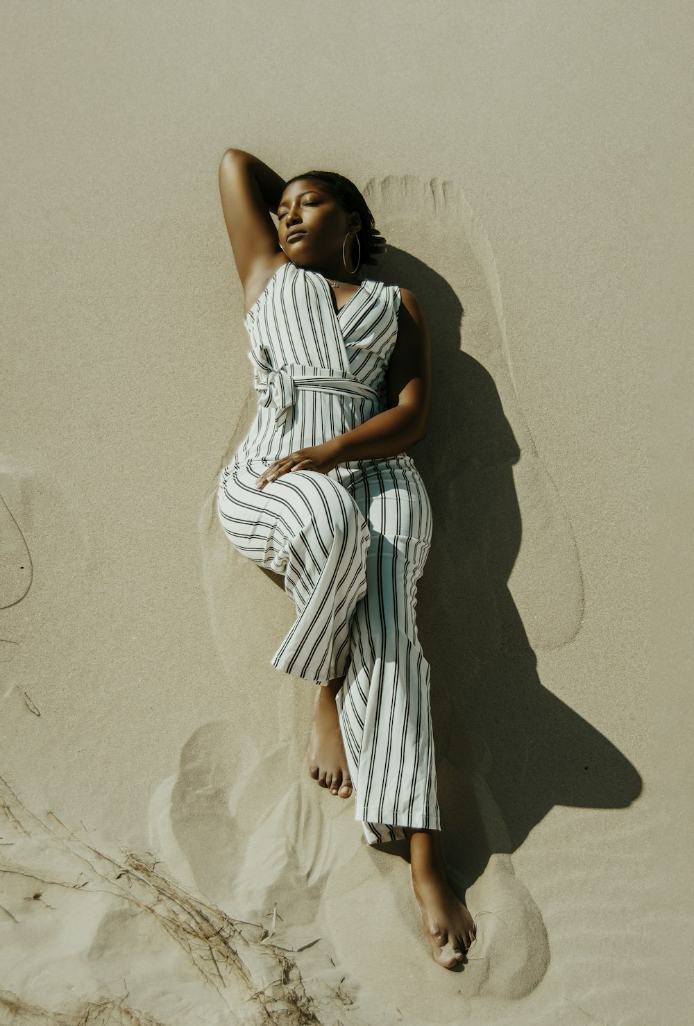 mujer con vestido de rayas blancas y negras de pie sobre la arena