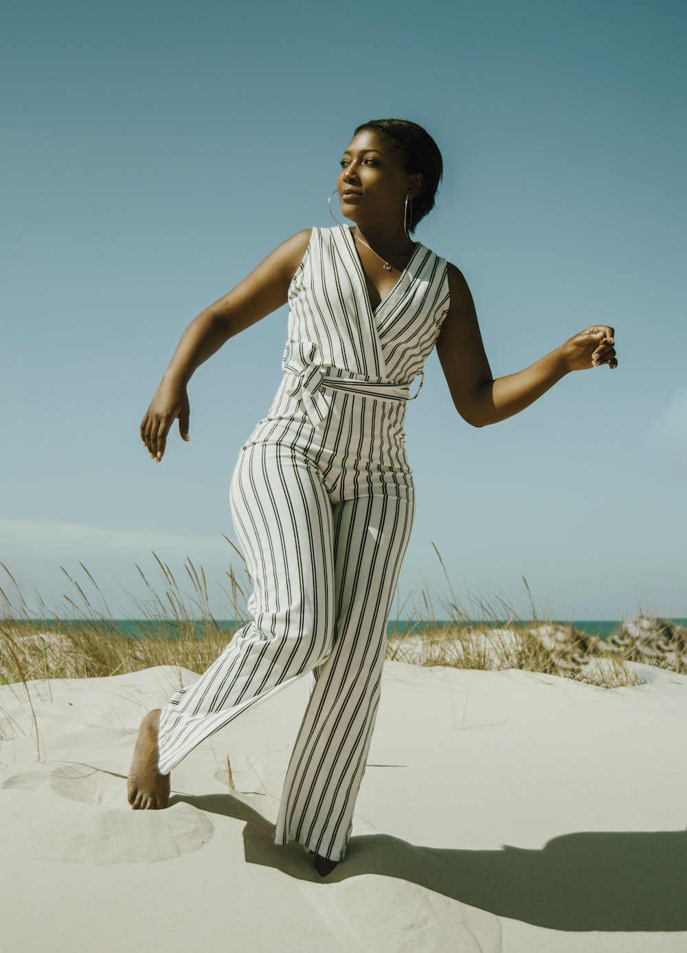 woman in white and black stripe dress standing on white sand during daytime