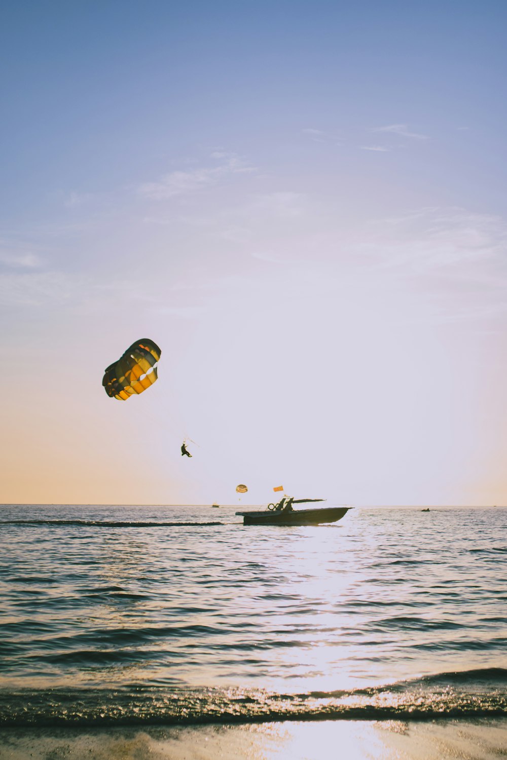 person in yellow and blue parachute over the sea during daytime