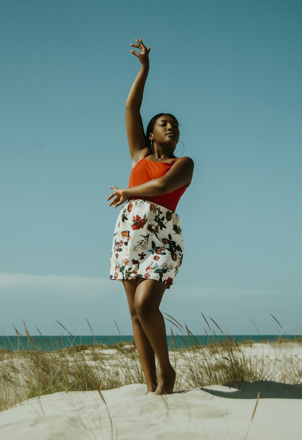 woman in white and red floral dress standing on green grass field during daytime