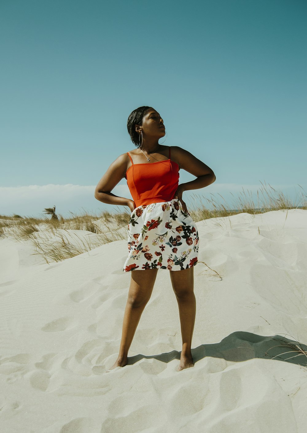 woman in blue and white floral dress standing on white sand during daytime