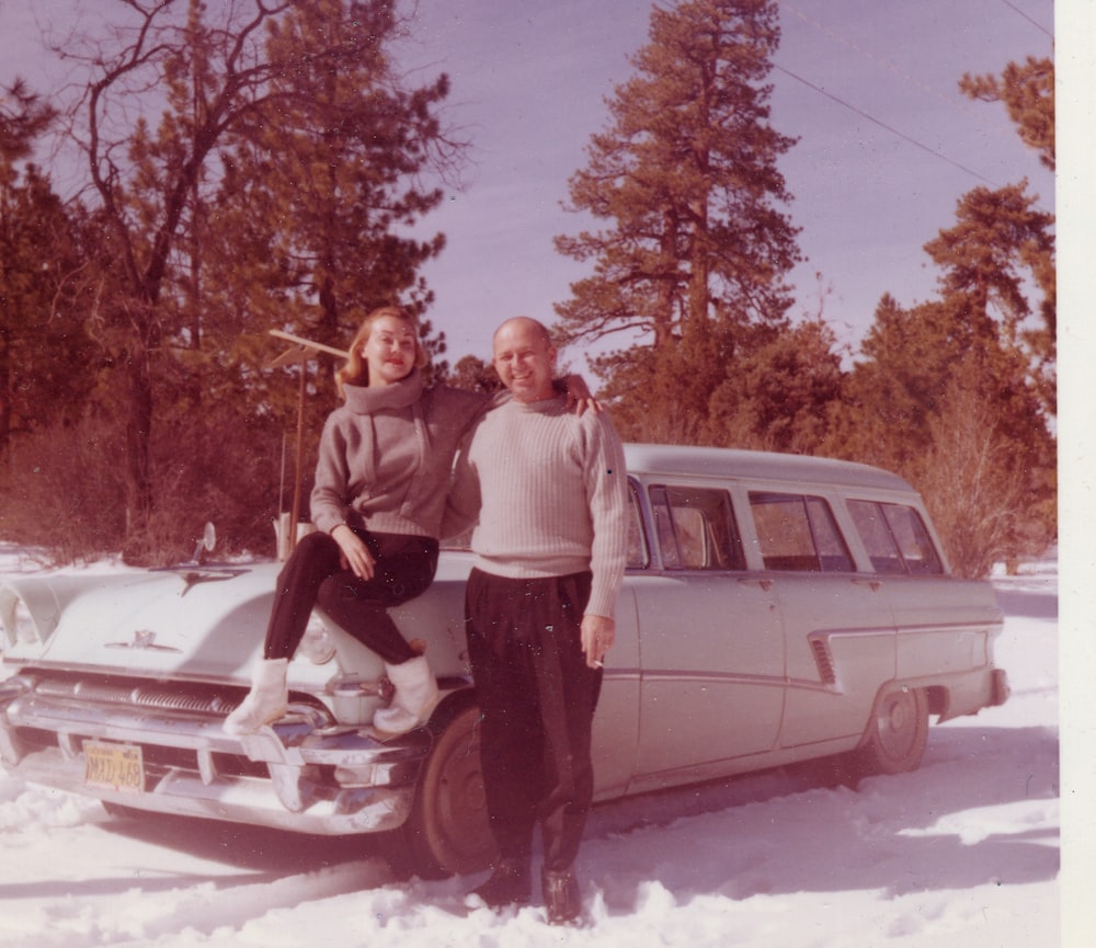 3 men standing beside white car on snow covered ground during daytime