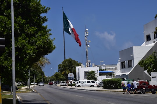 white and red flag on pole near road during daytime in Quintana Roo Mexico