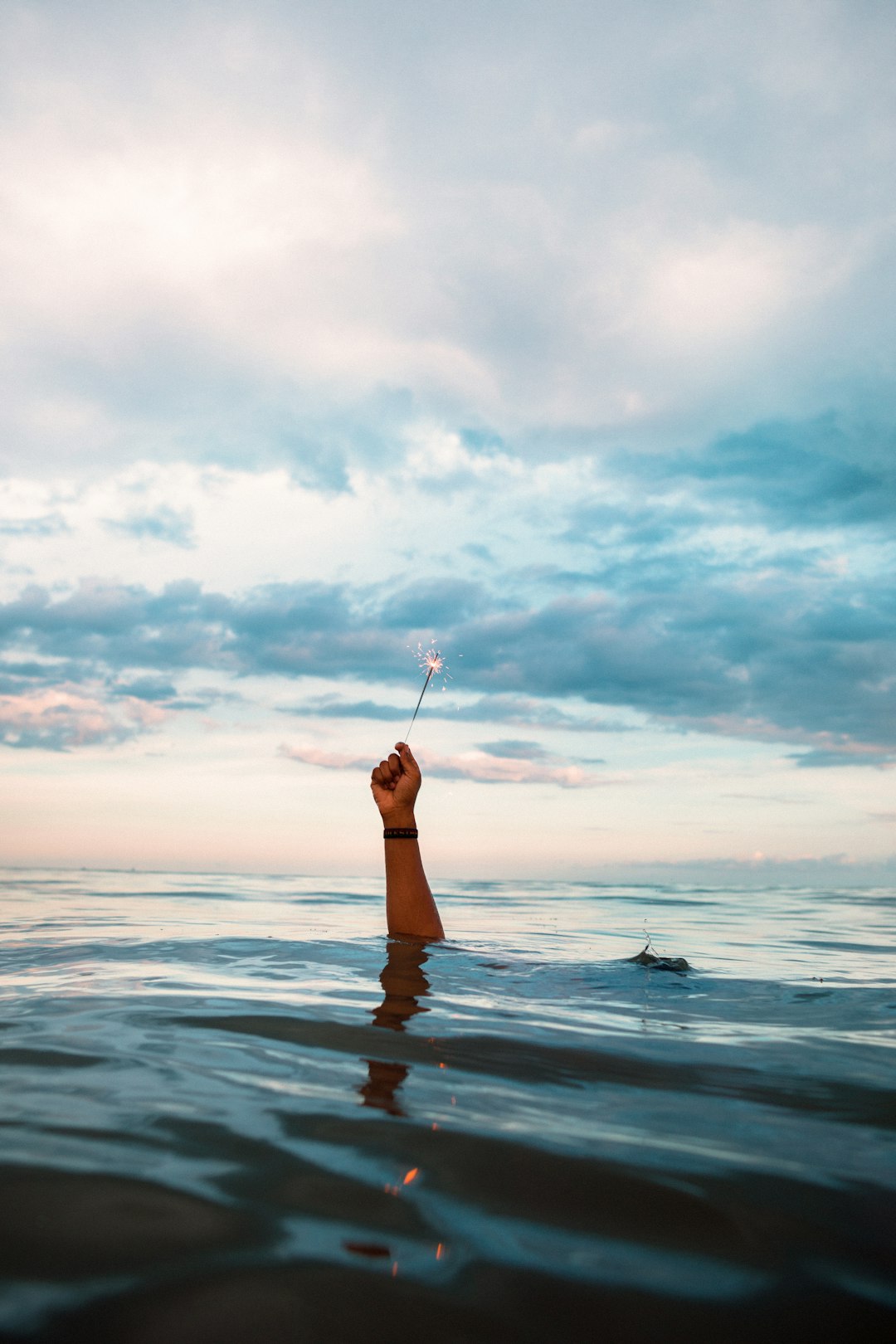 person in water holding stick during daytime