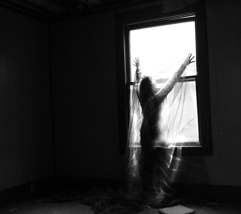 a woman standing in front of a window in a dark room