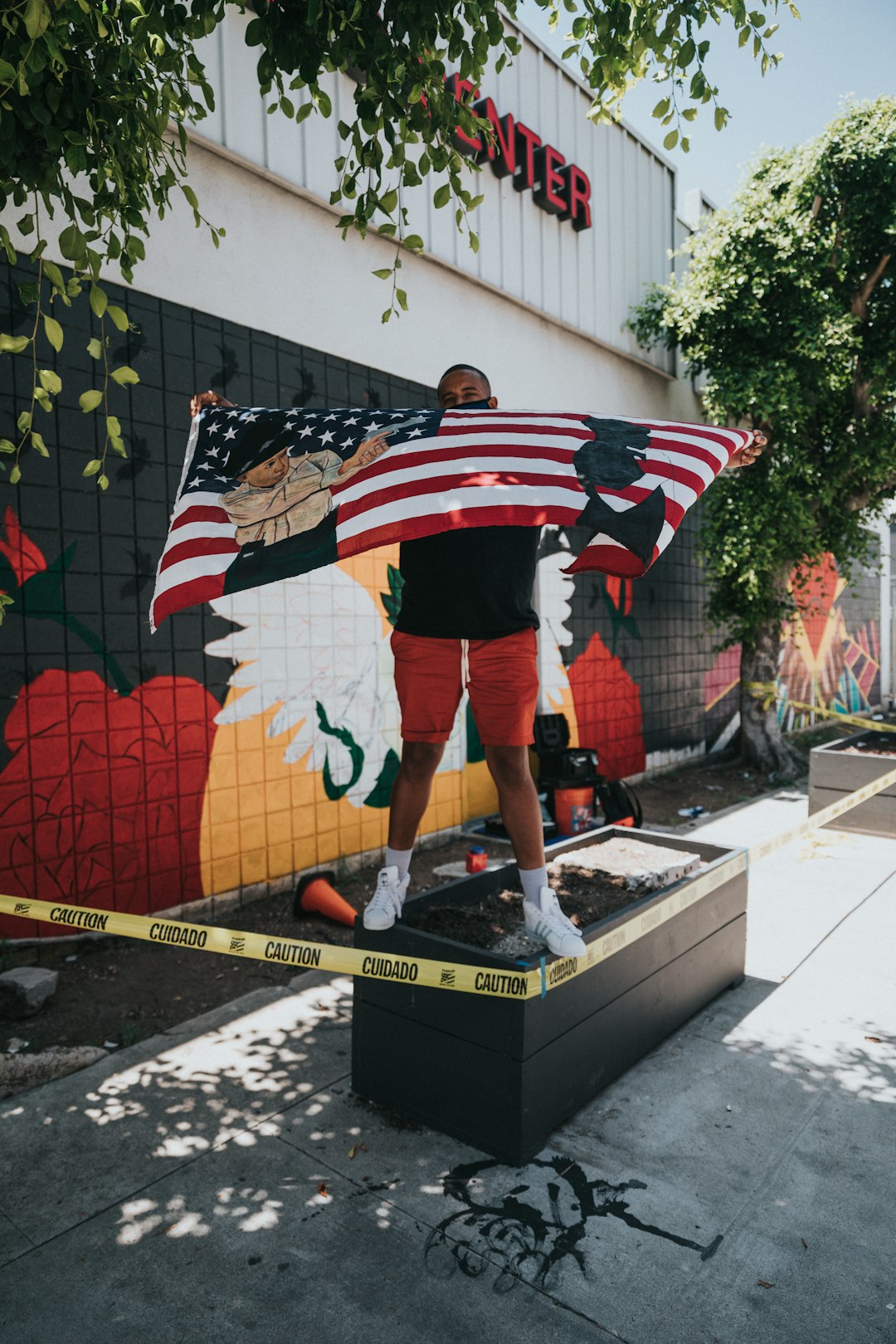 man in black white and red striped shirt standing beside us flag