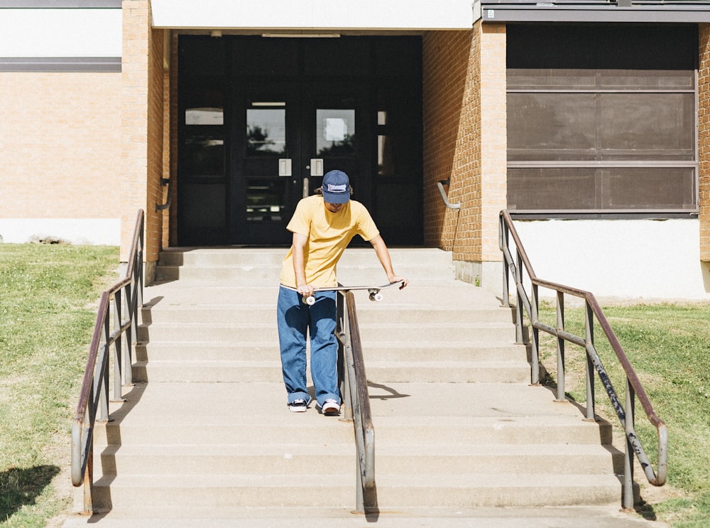 man in yellow t-shirt and blue denim jeans sitting on gray metal railings