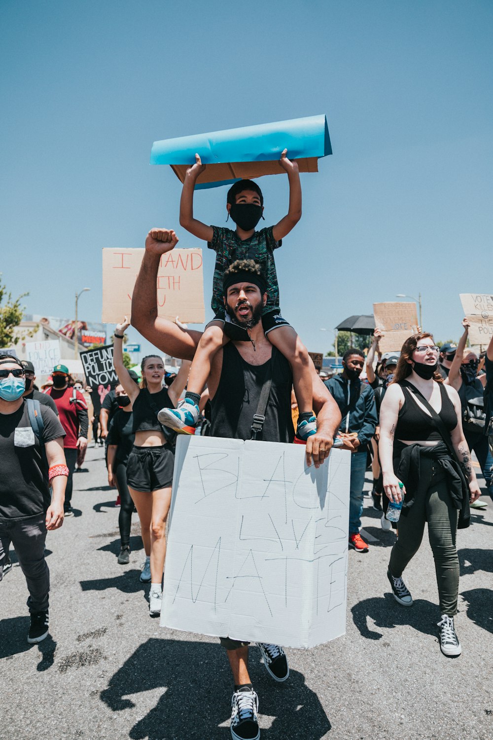 Personas con camisas negras y pantalones negros sosteniendo una caja de cartón marrón