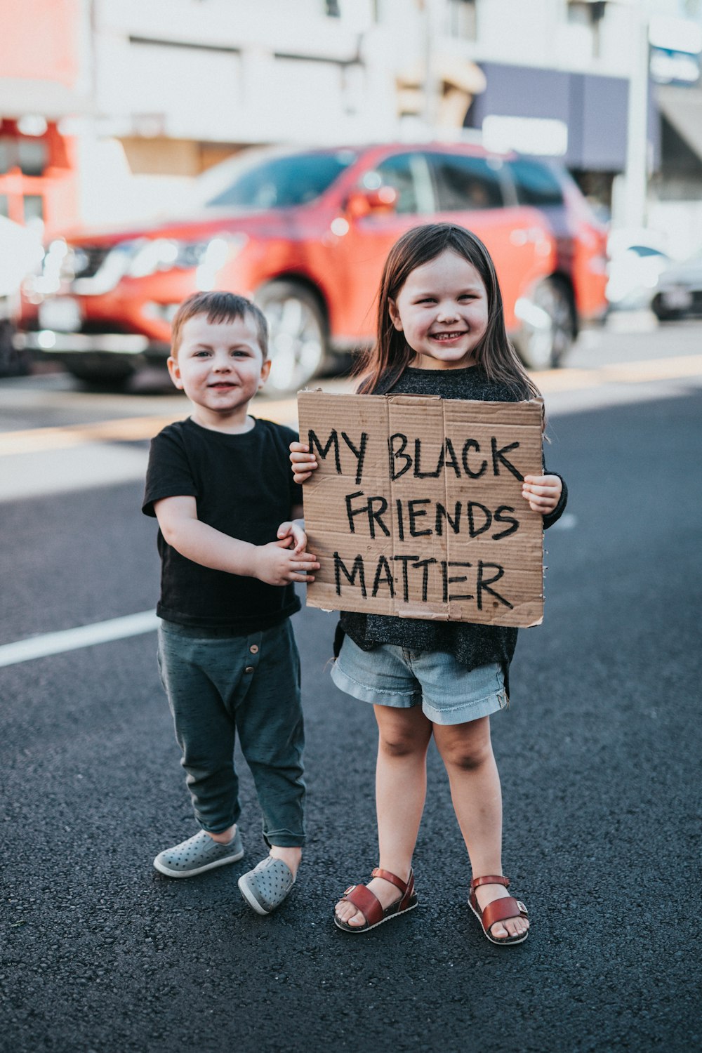 黒のTシャツを着た女の子と茶色の段ボール箱を持っている黒いTシャツの男の子