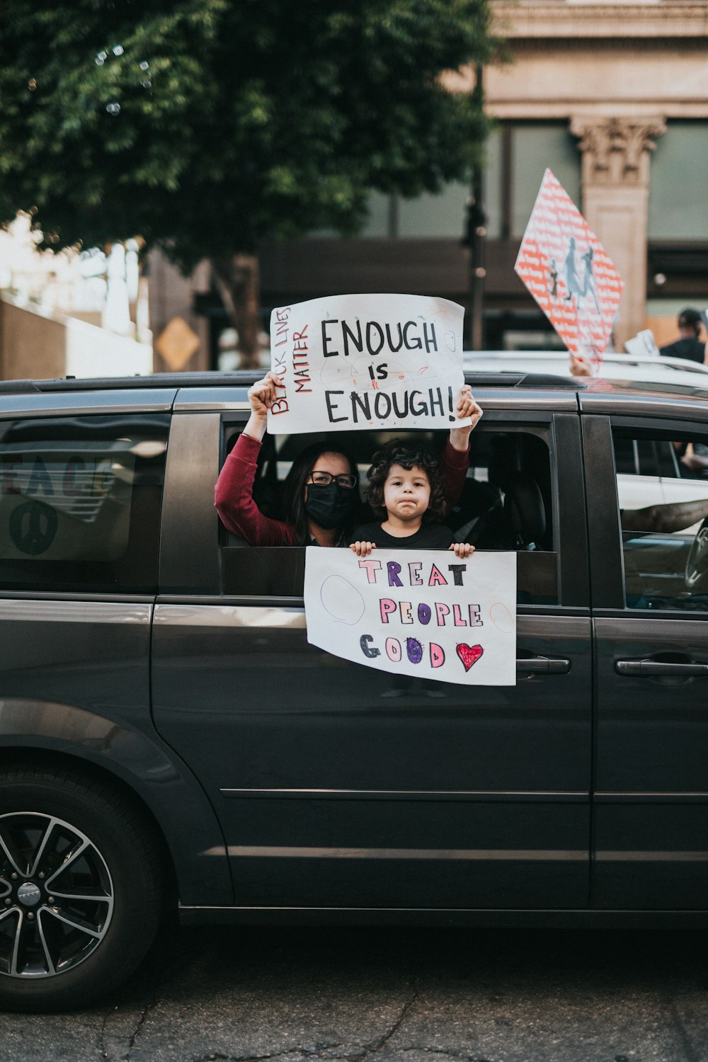 man in black jacket holding white and blue signage