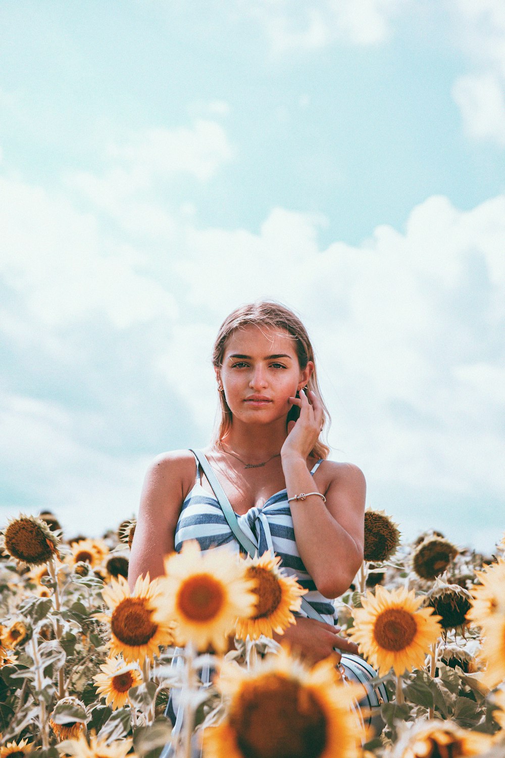 woman in blue tank top holding sunflower during daytime