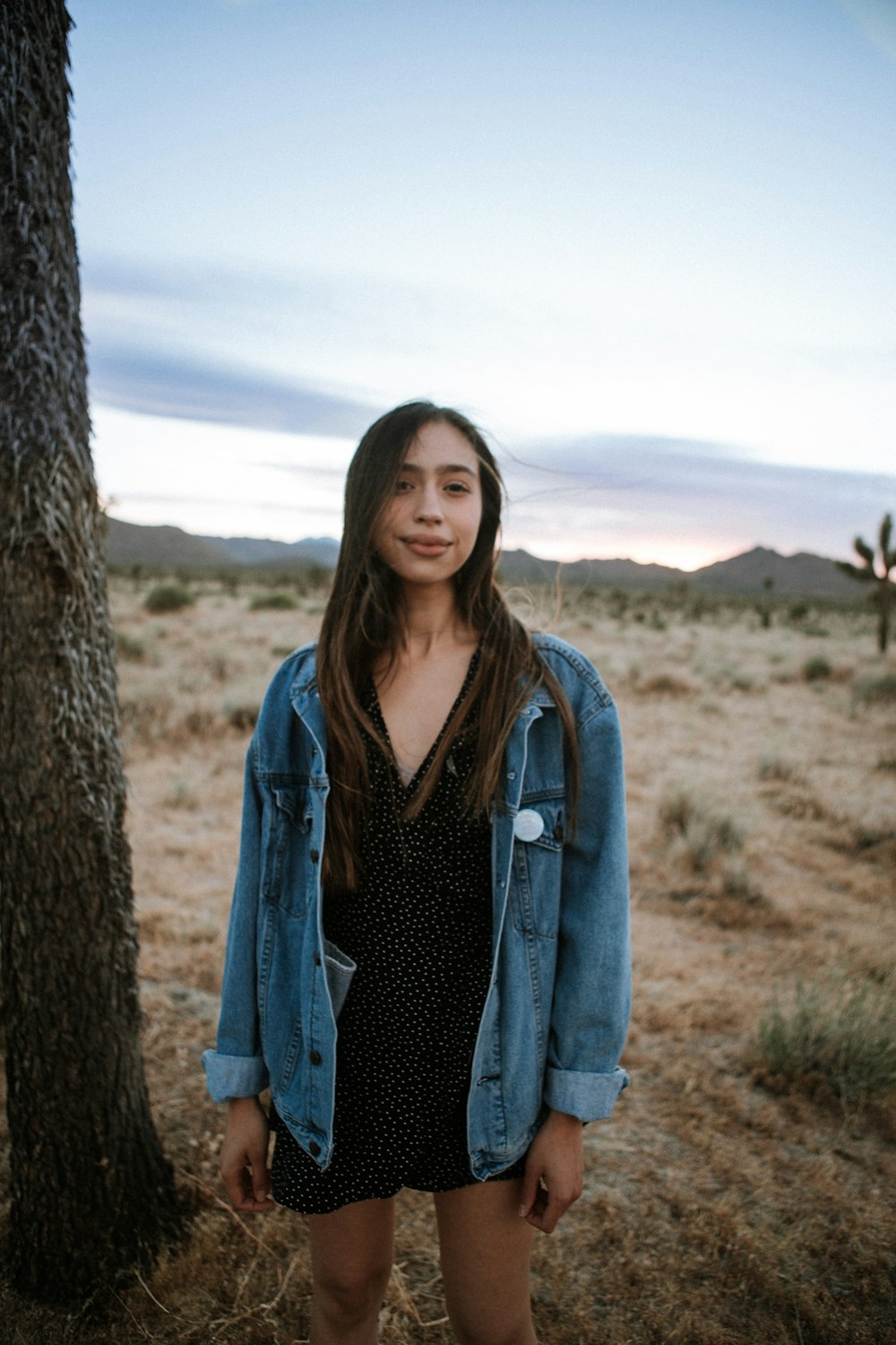 woman in blue denim jacket standing near brown rock during daytime