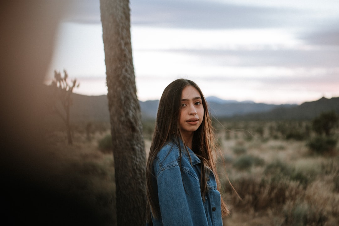 woman in blue denim jacket standing near brown tree during daytime