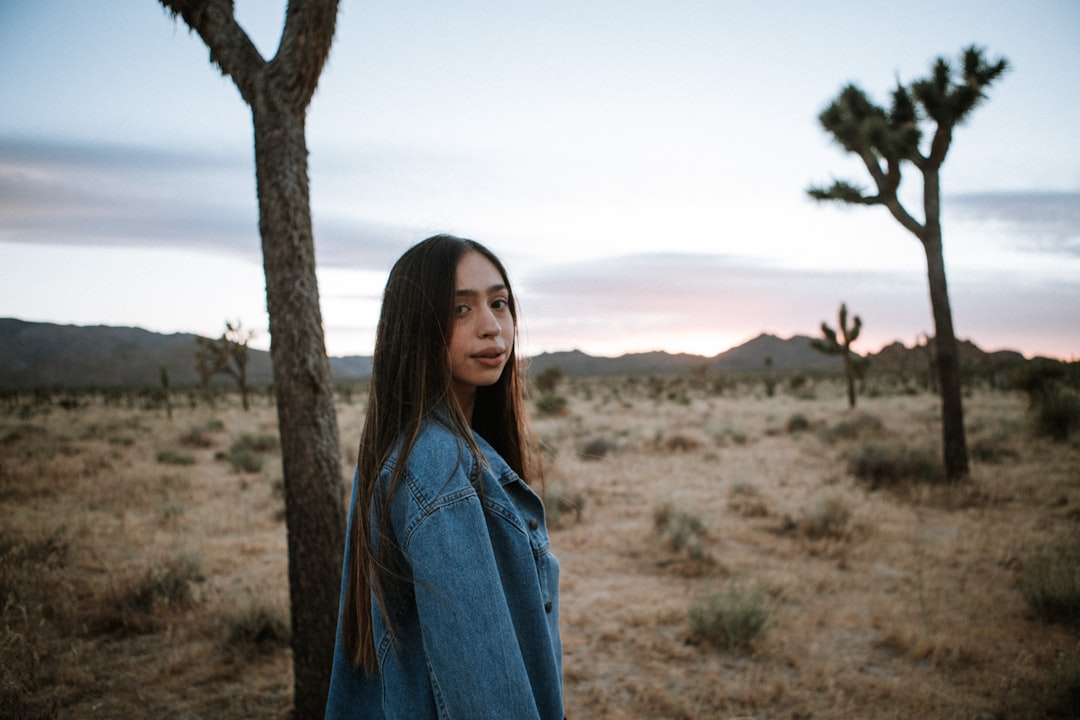 woman in blue denim jacket standing near brown tree during daytime