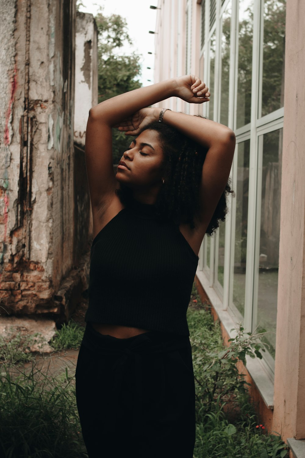 woman in black tank top standing near brown tree trunk during daytime