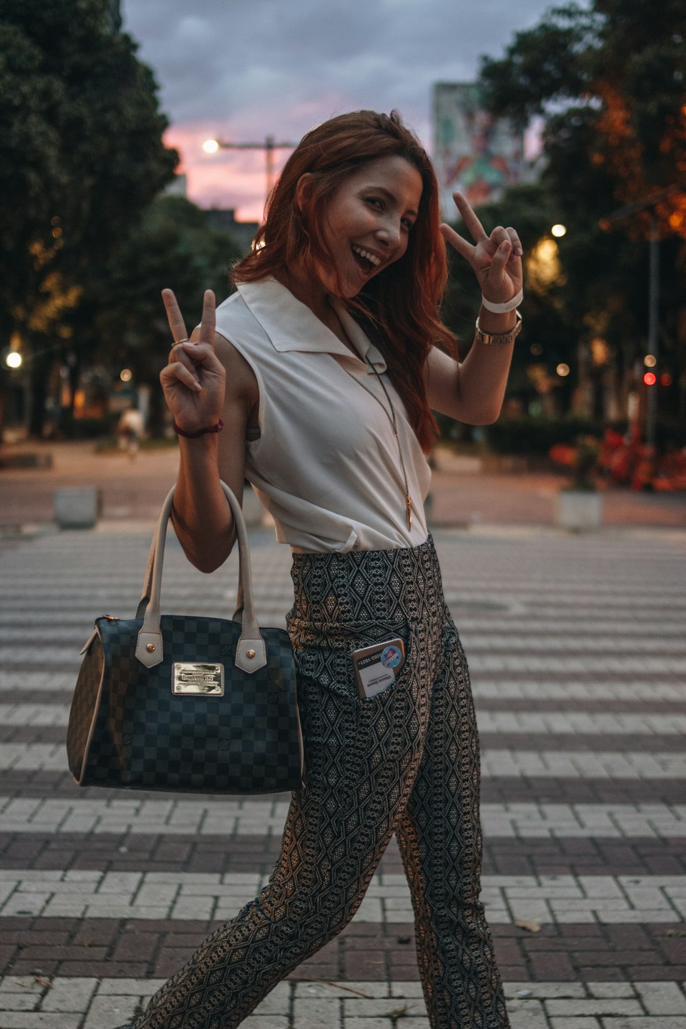 woman in white shirt and black and white skirt holding black leather handbag