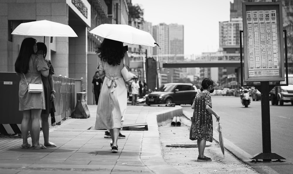 woman in white coat holding umbrella walking on sidewalk during daytime